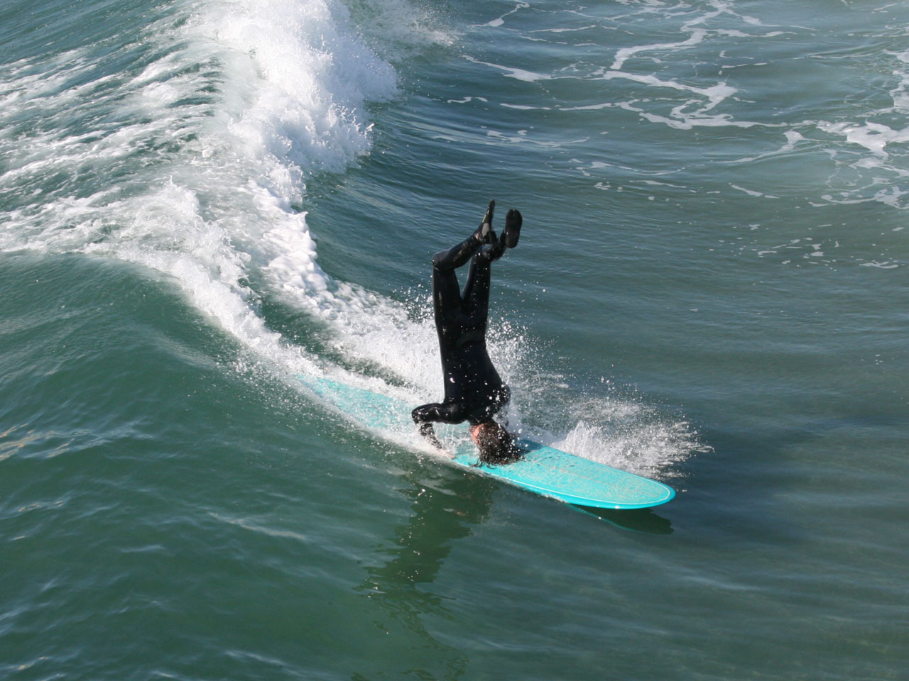 Longboard surfer doet een headstand