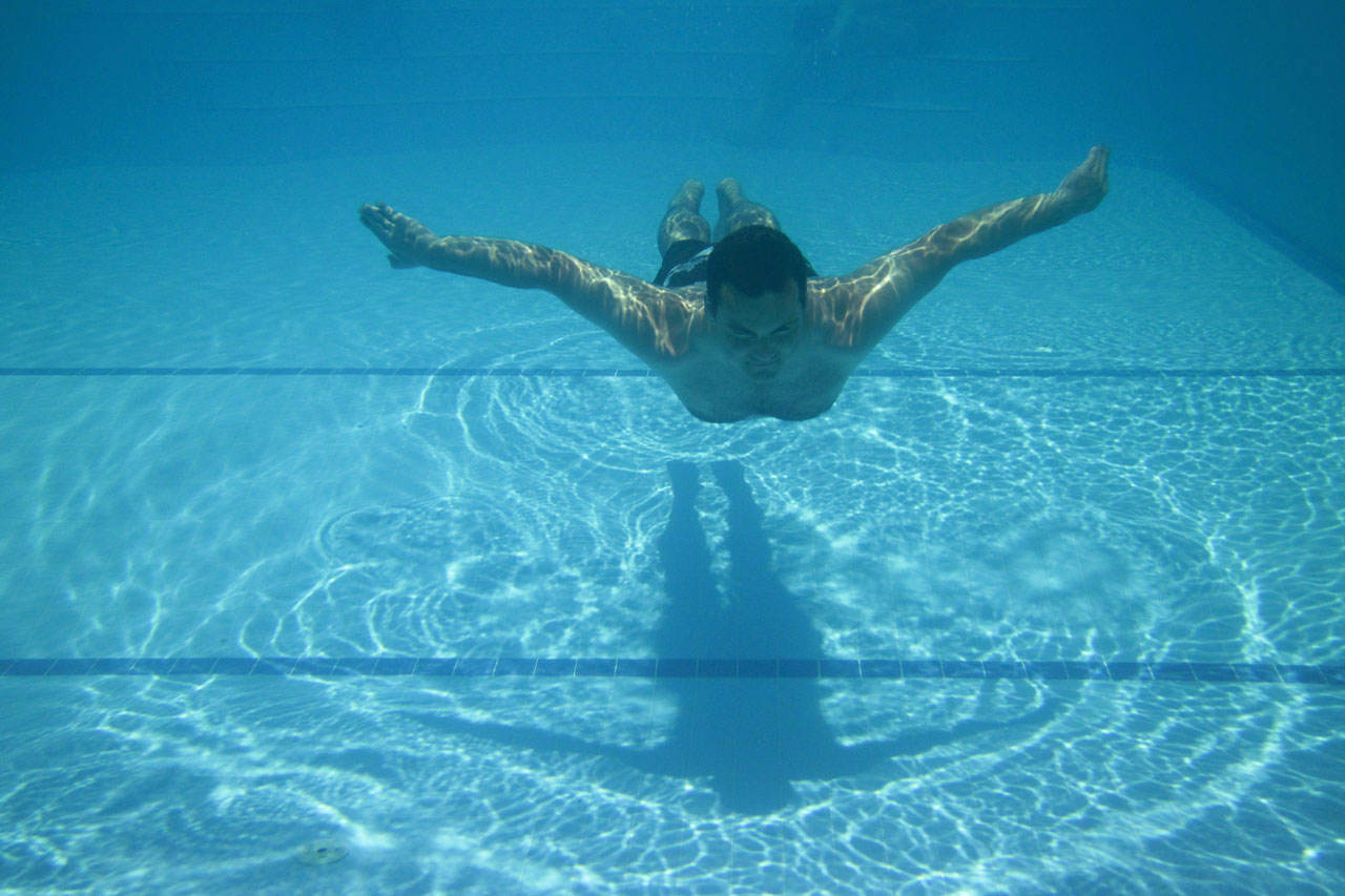 Ember úszik a medencében