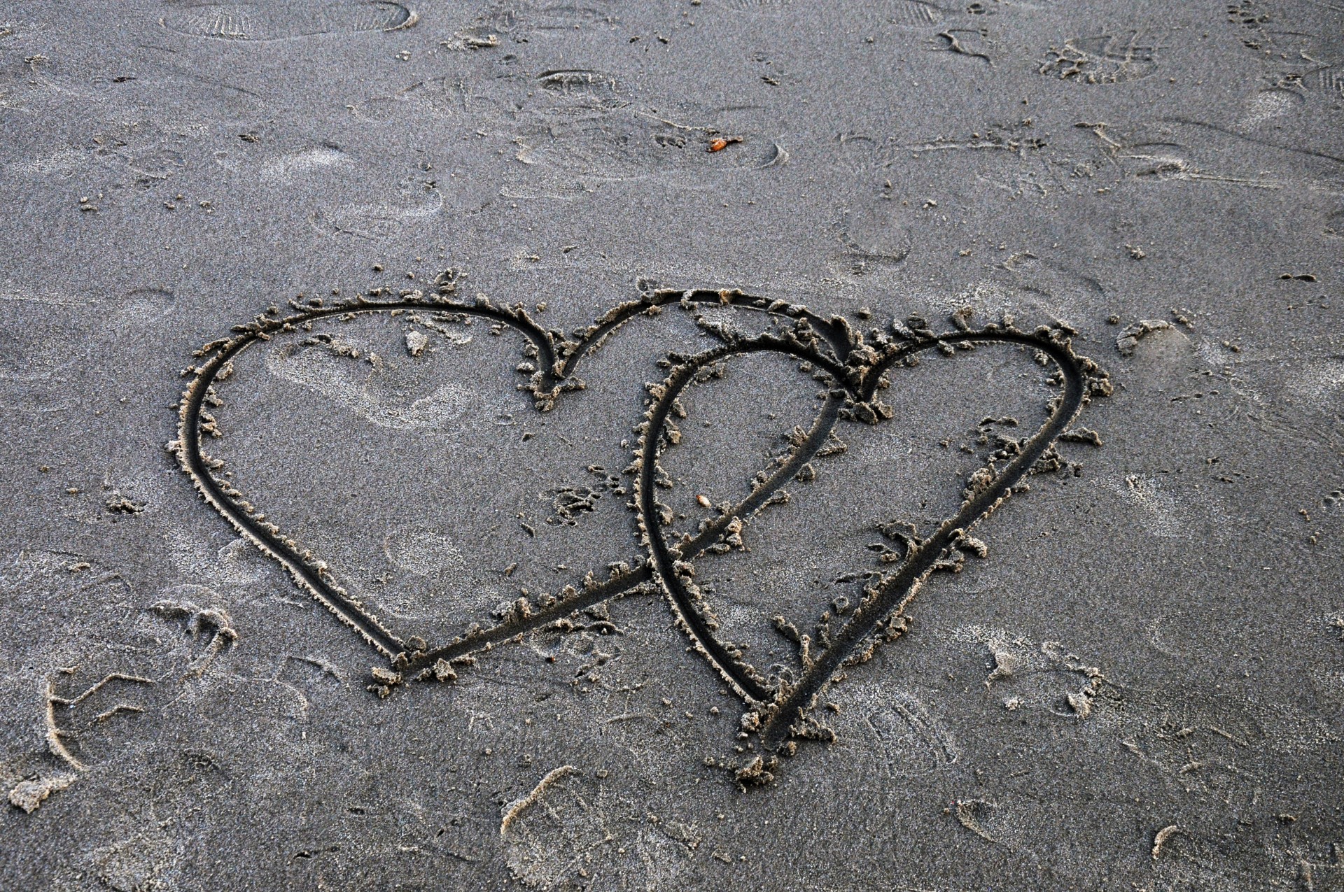 Două inimi care se suprapun în nisip