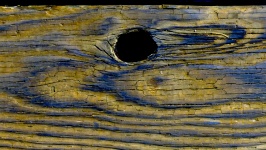 Knothole In Blue And Yellow Wood