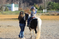 Kleines Mädchen auf Pferd mit Mom