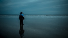 Мальчик, стоя на пляже