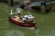 Modell båt i dammen bredvid brygga
