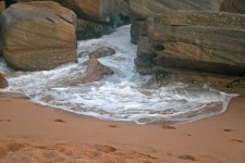 Sea foam pushing through rocks