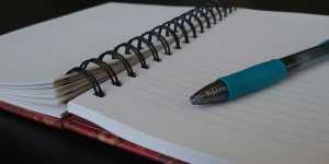Öppna anteckningsboken med blå penna