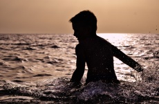 Toddler chapoteando en el mar por Sun