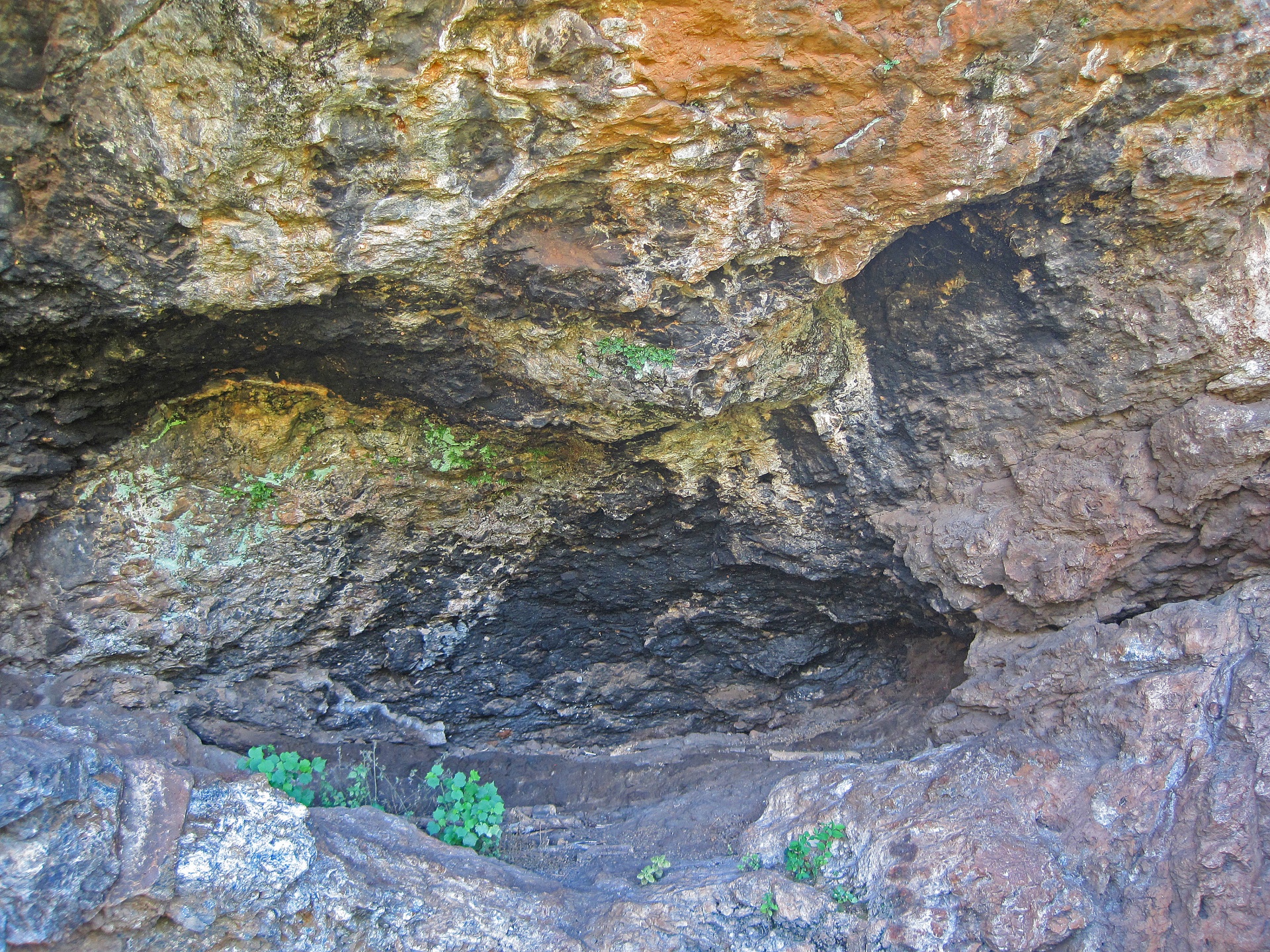 Zwartgeblakerde opening van de grot
