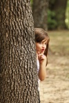 Fată mică ascunsă în spatele copacului