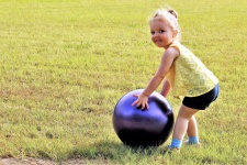 Liten flicka som leker med stor boll