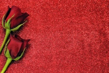 Dvě červené růže na červeném třpytu
