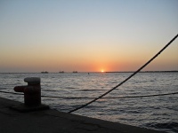 Solnedgång över havet med bollard