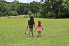 Young Sisters Walking In Field