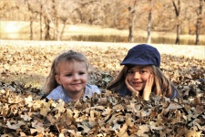 Twee kleine meisjes liggen in bladeren