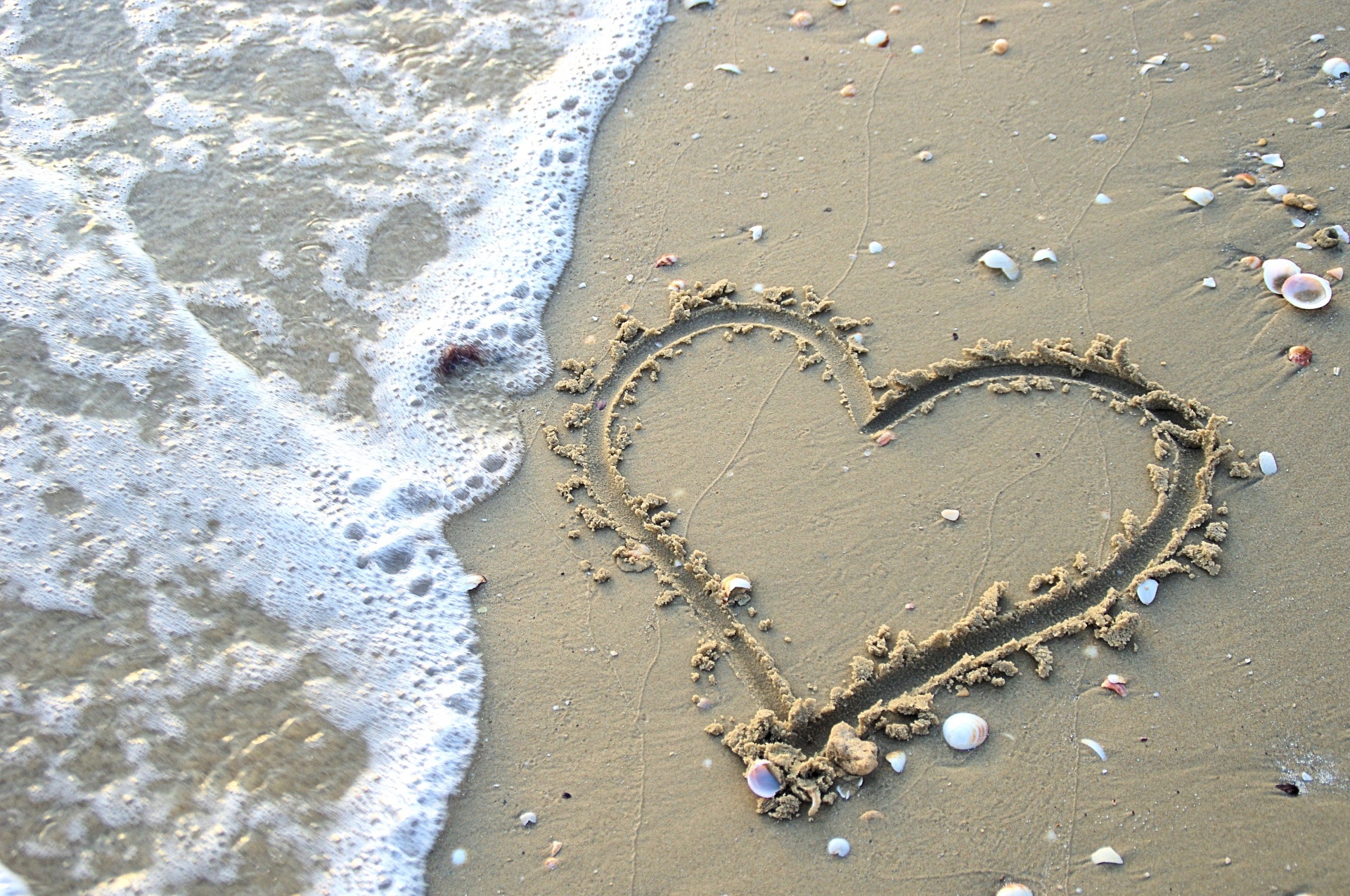 Rita hjärtan i sanden