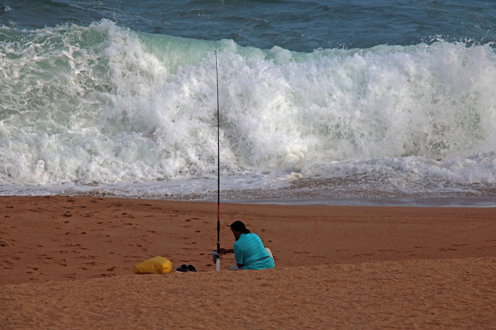 Rybář sedí na pláži