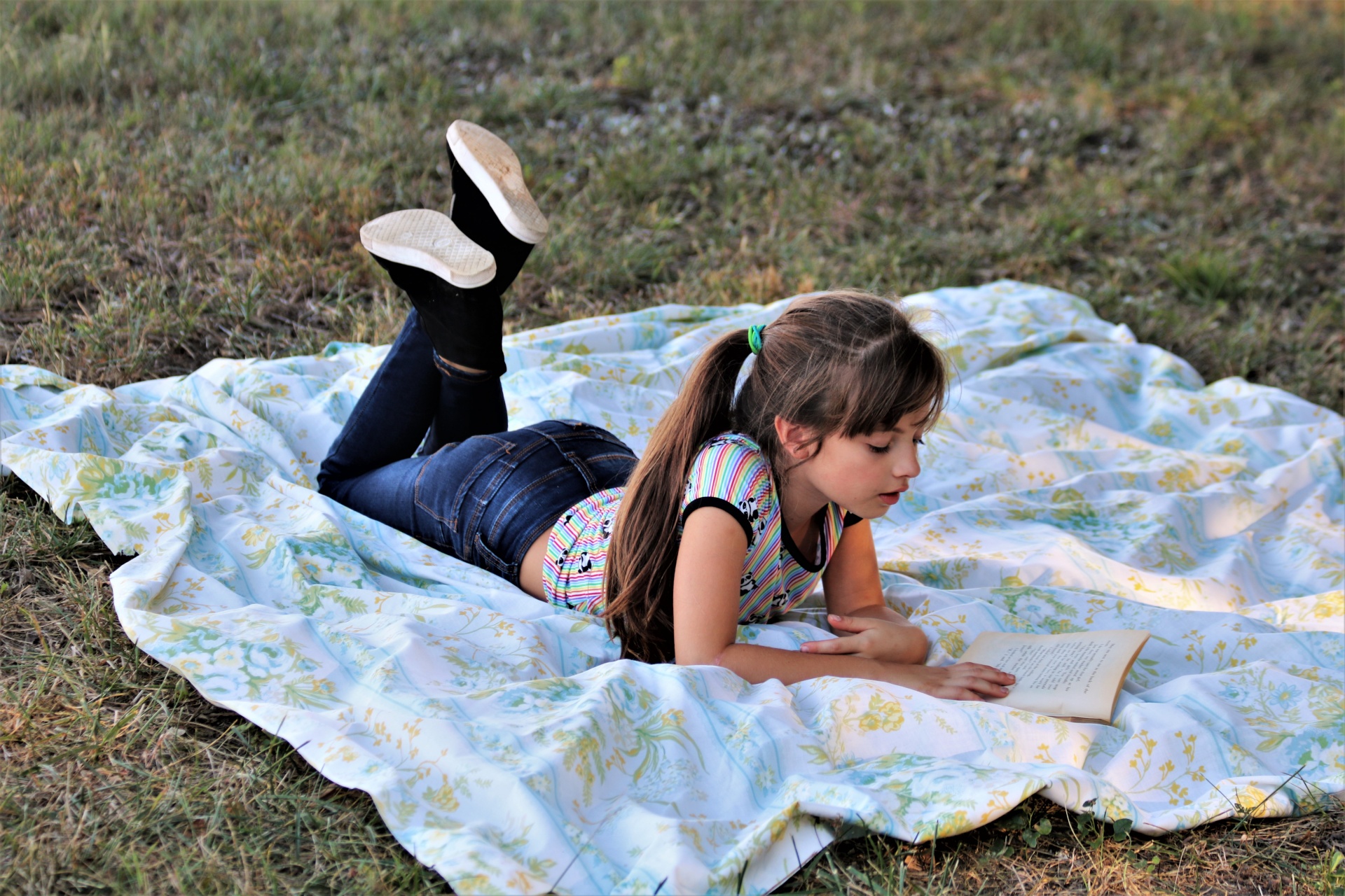 Mladá dívka čtení knihy v trávě