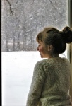 Mädchen, das Schnee durch Fenster betrac