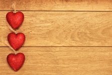Trei inimi de sclipici roșii pe lemn