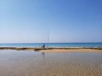 Рыбак с удочкой на пляже