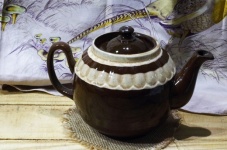 Brązowy ceramiczny czajniczek na drewnie