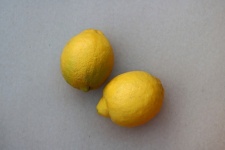 Two yellow lemons on white surface