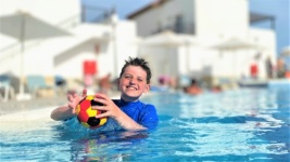 Băiat în piscină de vacanță cu minge