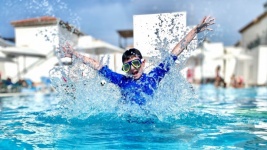 Pojke hoppar i poolen på semester
