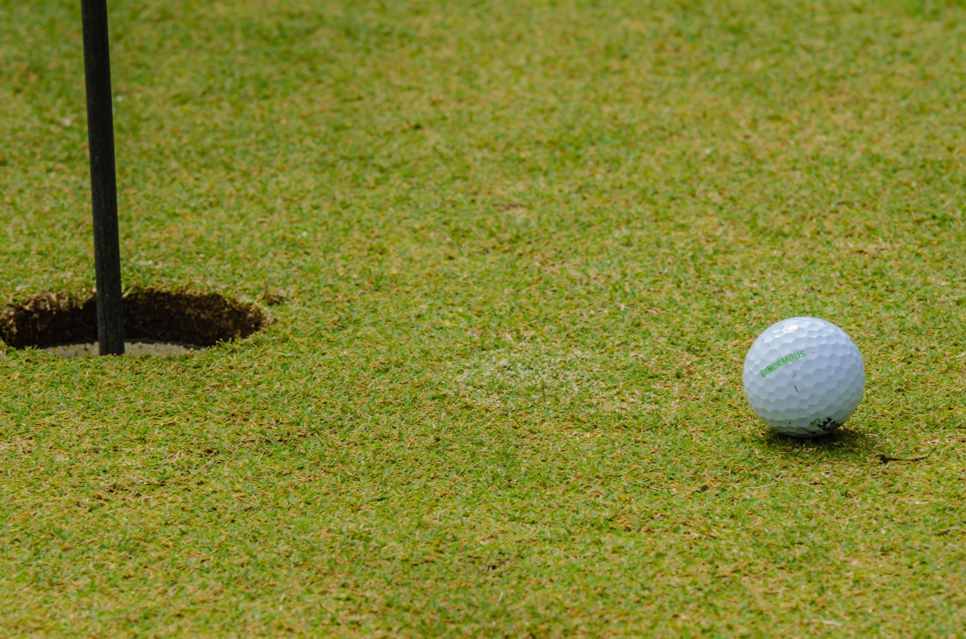 Мяч для гольфа рядом с отверстием