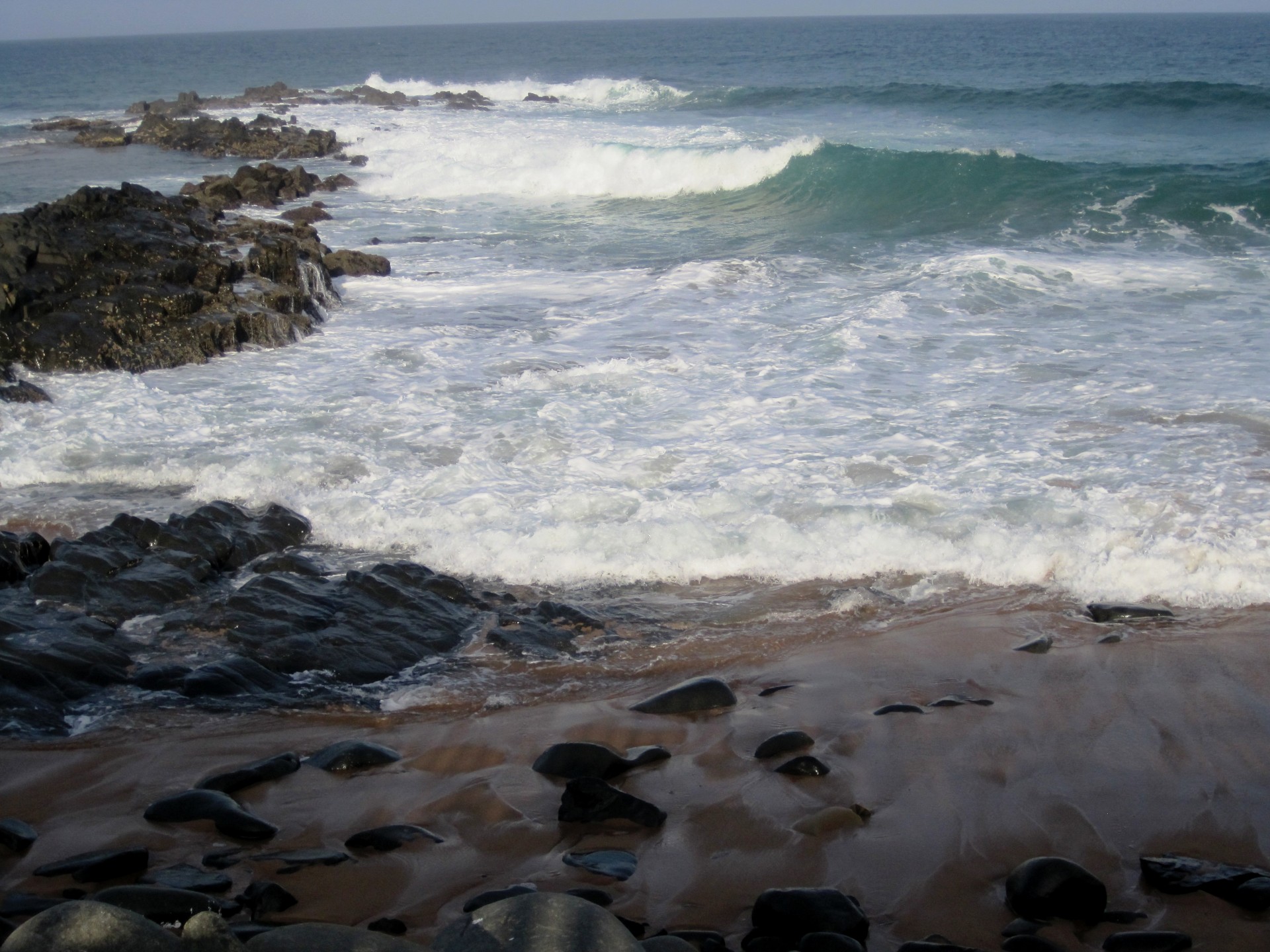 Welle bricht am Strand