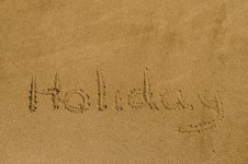 "Holiday" written in the sand