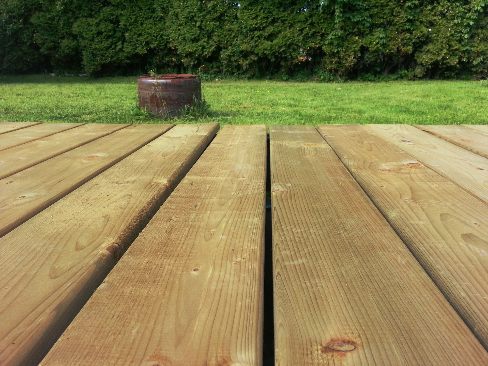 A wooden deck next to a grass lawn